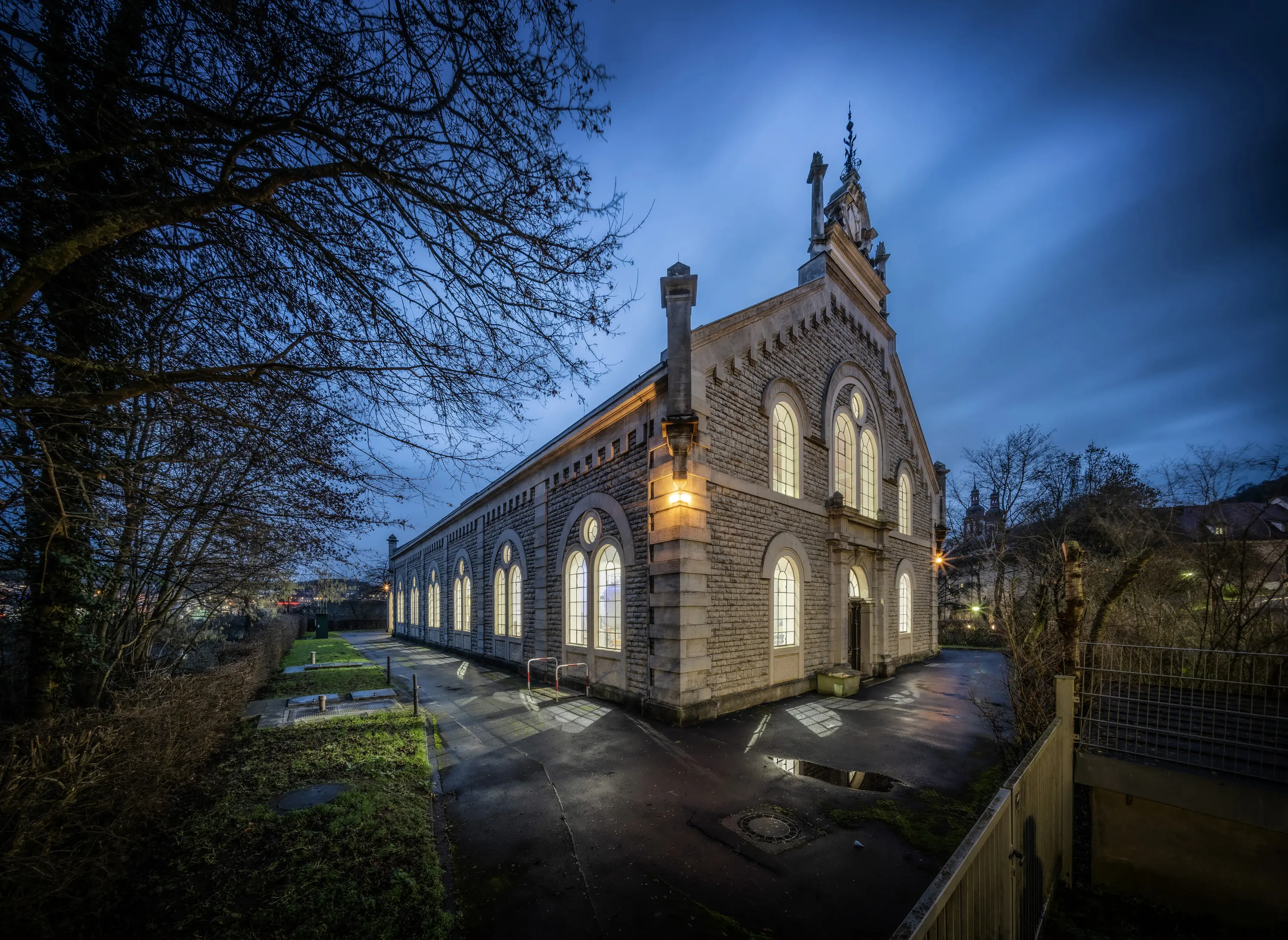 Historisches Wasserwerk Würzburg-Zell mit beleuchteten Fenstern am Abend