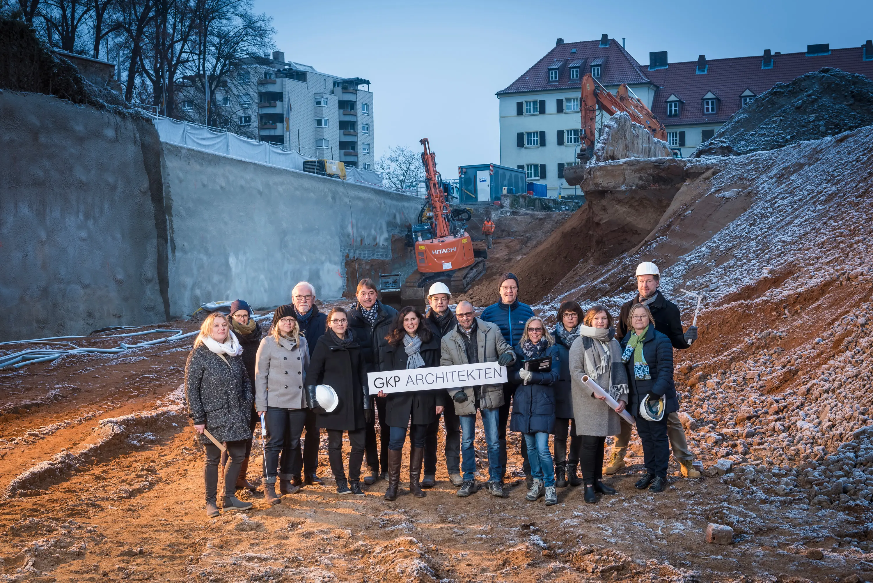 Bauherren und Planer mit Bauhelmen in der Baugrube beim Spatenstich