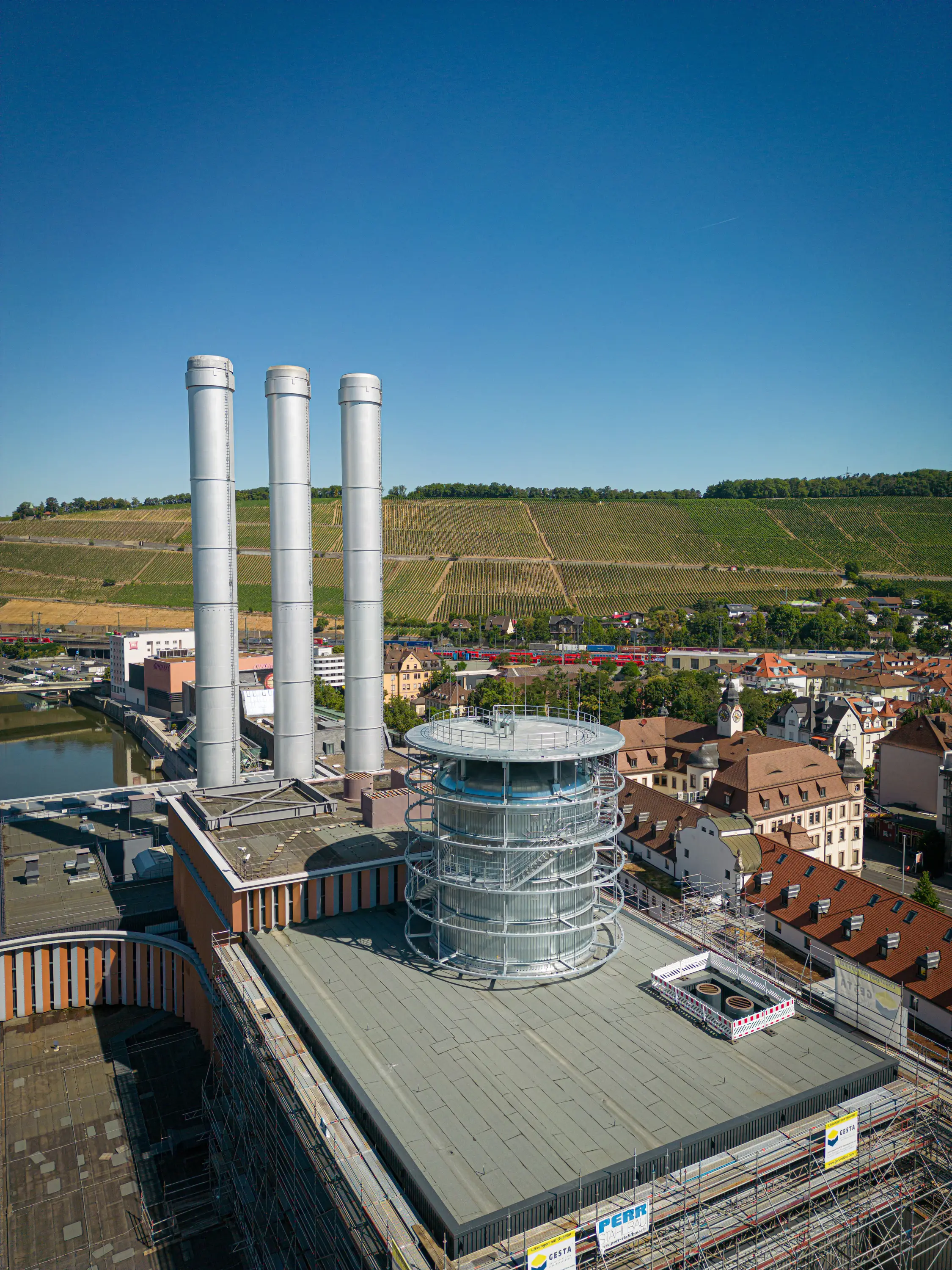 Renoviertes Heizkraftwerk Würzburg mit drei Schornsteinen vor den Weinbergen