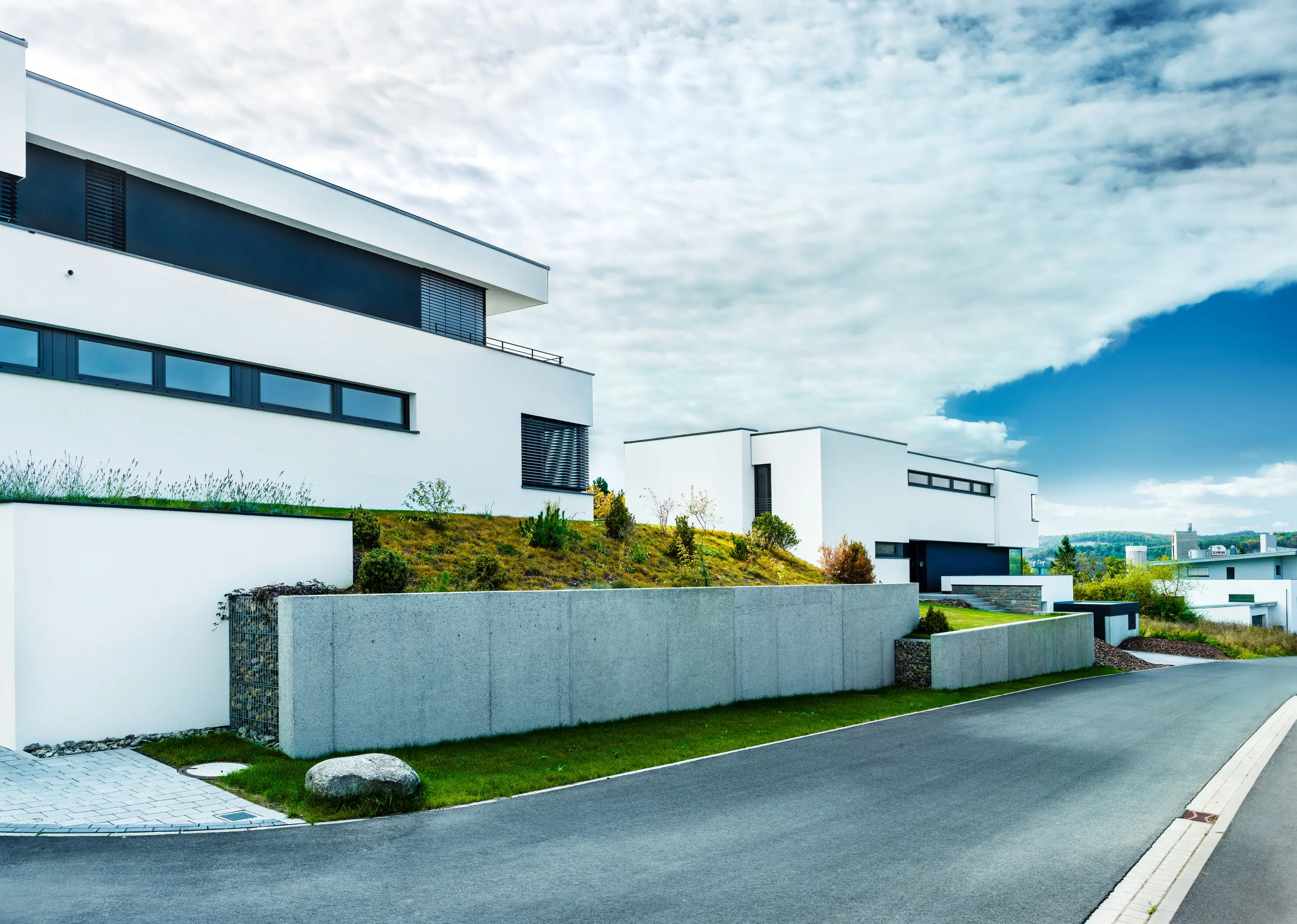 Villa am Hang mit Gartenmauer und Zufahrt