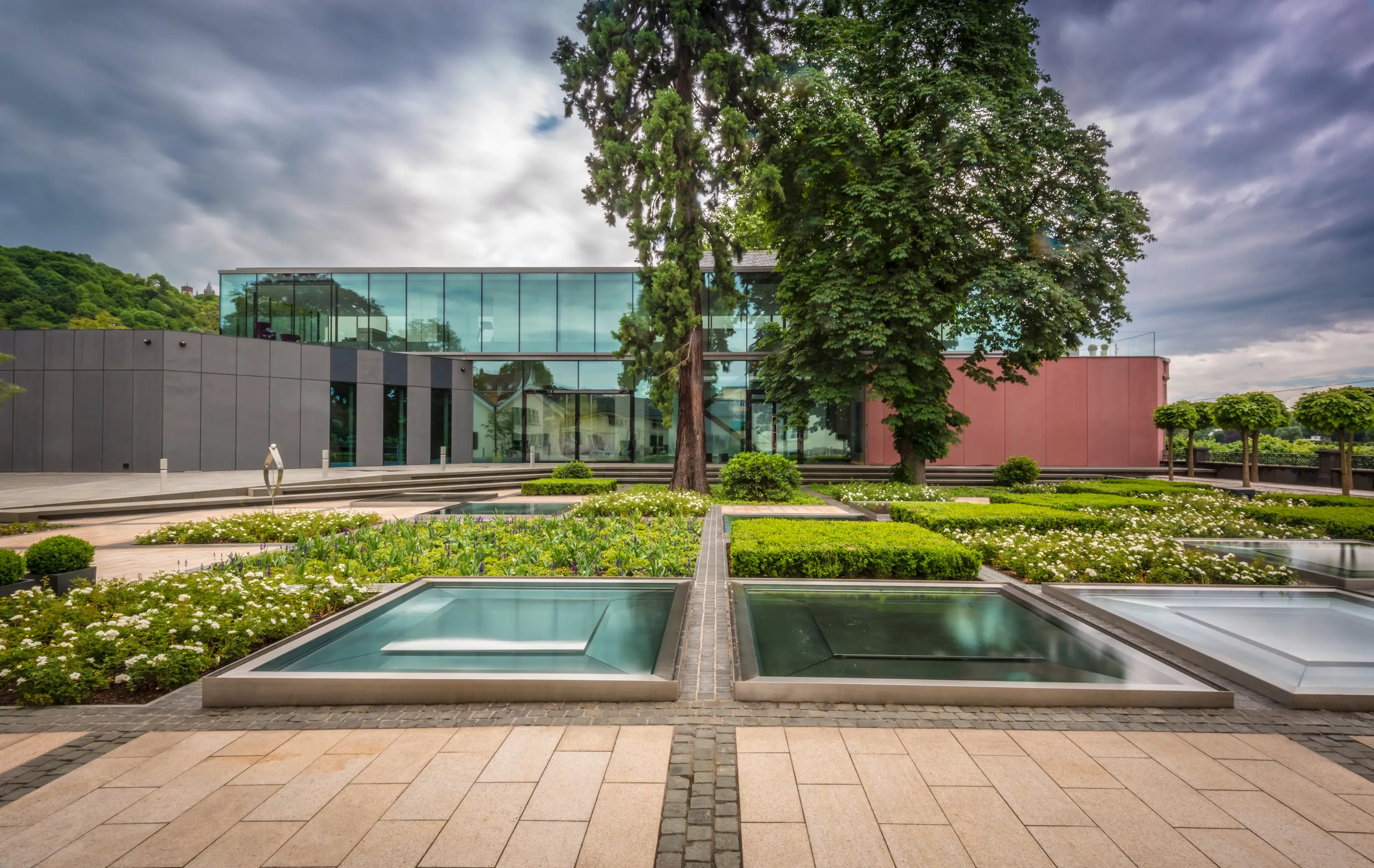 Garten mit Wasserbecken vor einem Gebäude mit Glasfassade