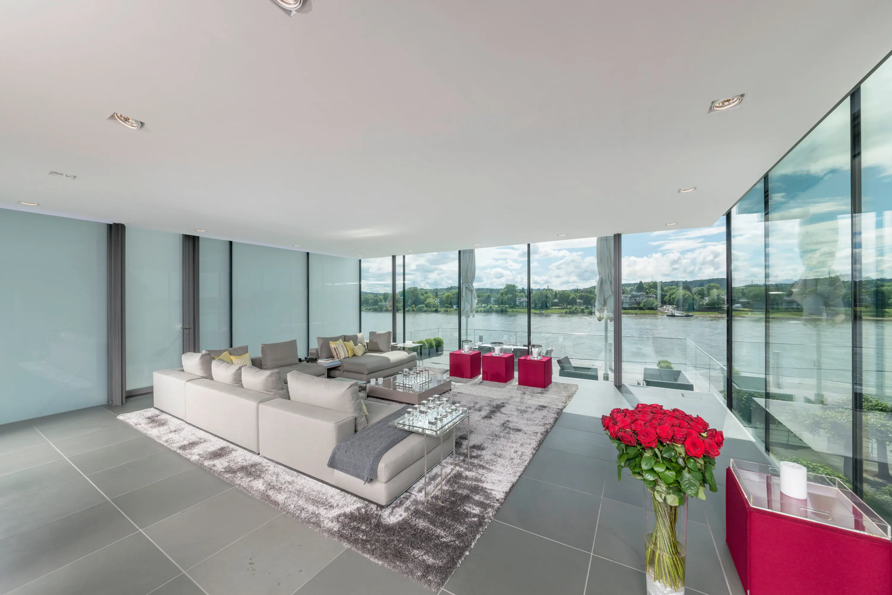 Wohnbereich mit Sofa und raumhoher Glasfront zum Wasser
