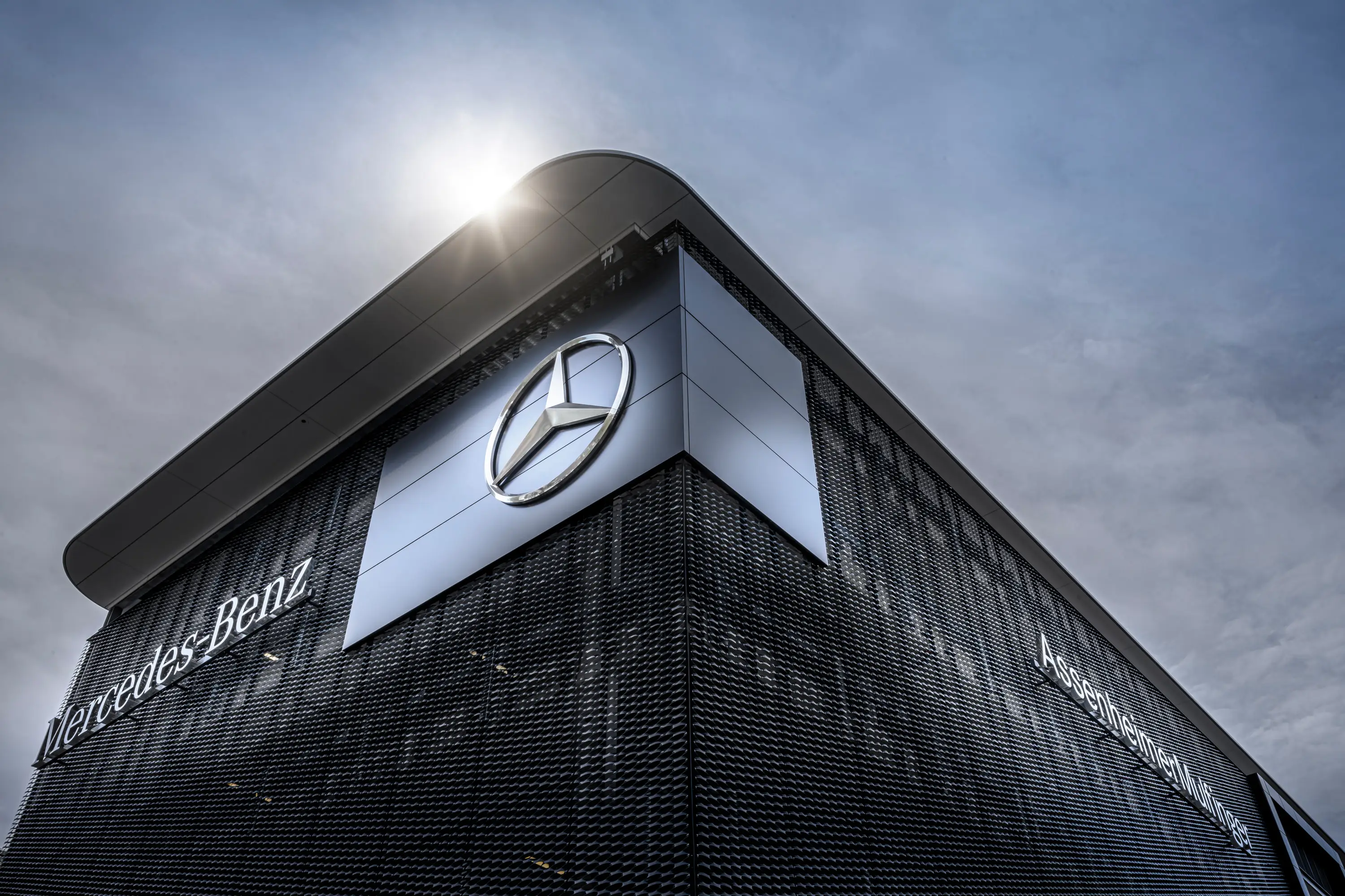 Mercedes-Stern an der dunklen Fassade eines Autohauses