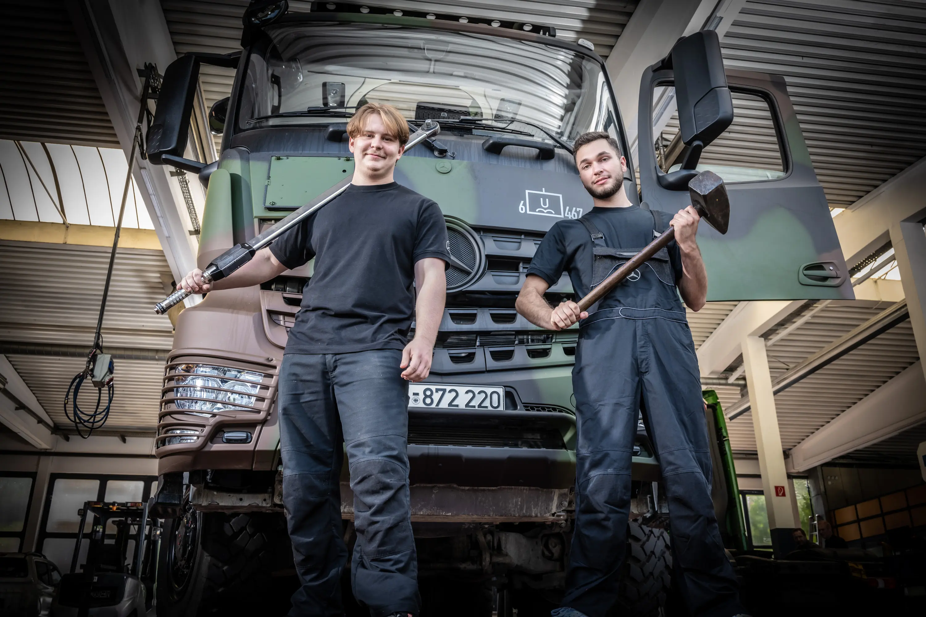 Zwei Mechaniker mit Werkzeug vor einem Lkw in der Werkstatt von Iglhaut