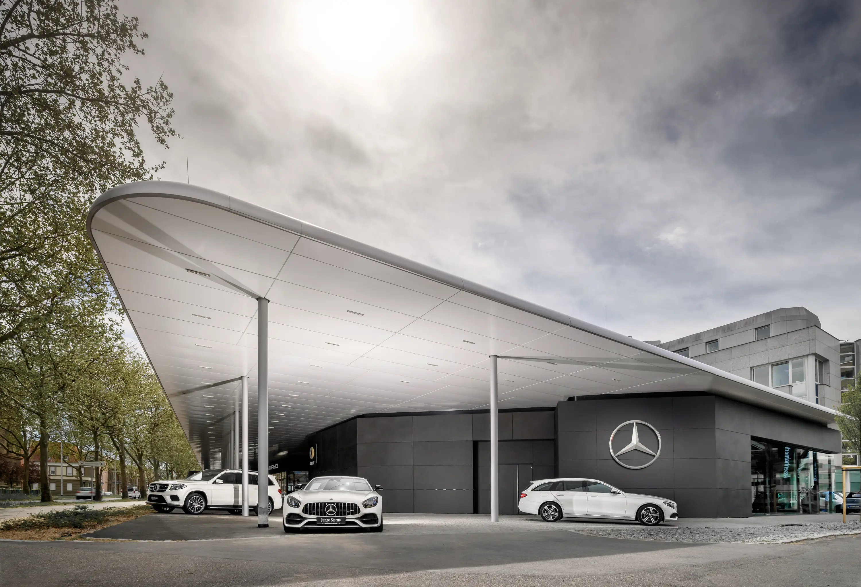 Geschwungenes Vordach eines Mercedes-Benz-Autohauses mit Fahrzeugen