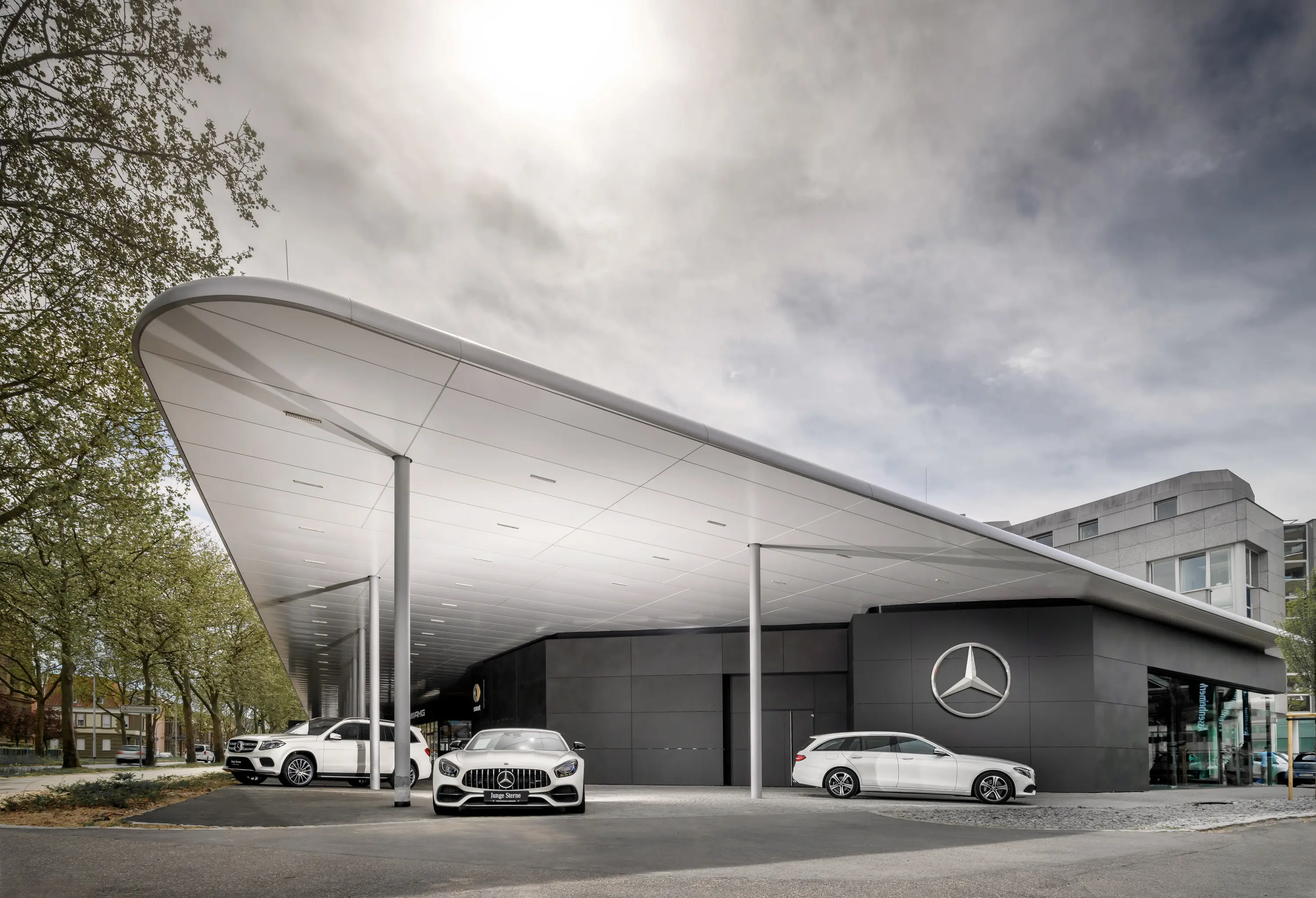 Geschwungenes Vordach eines Mercedes-Benz-Autohauses mit Fahrzeugen