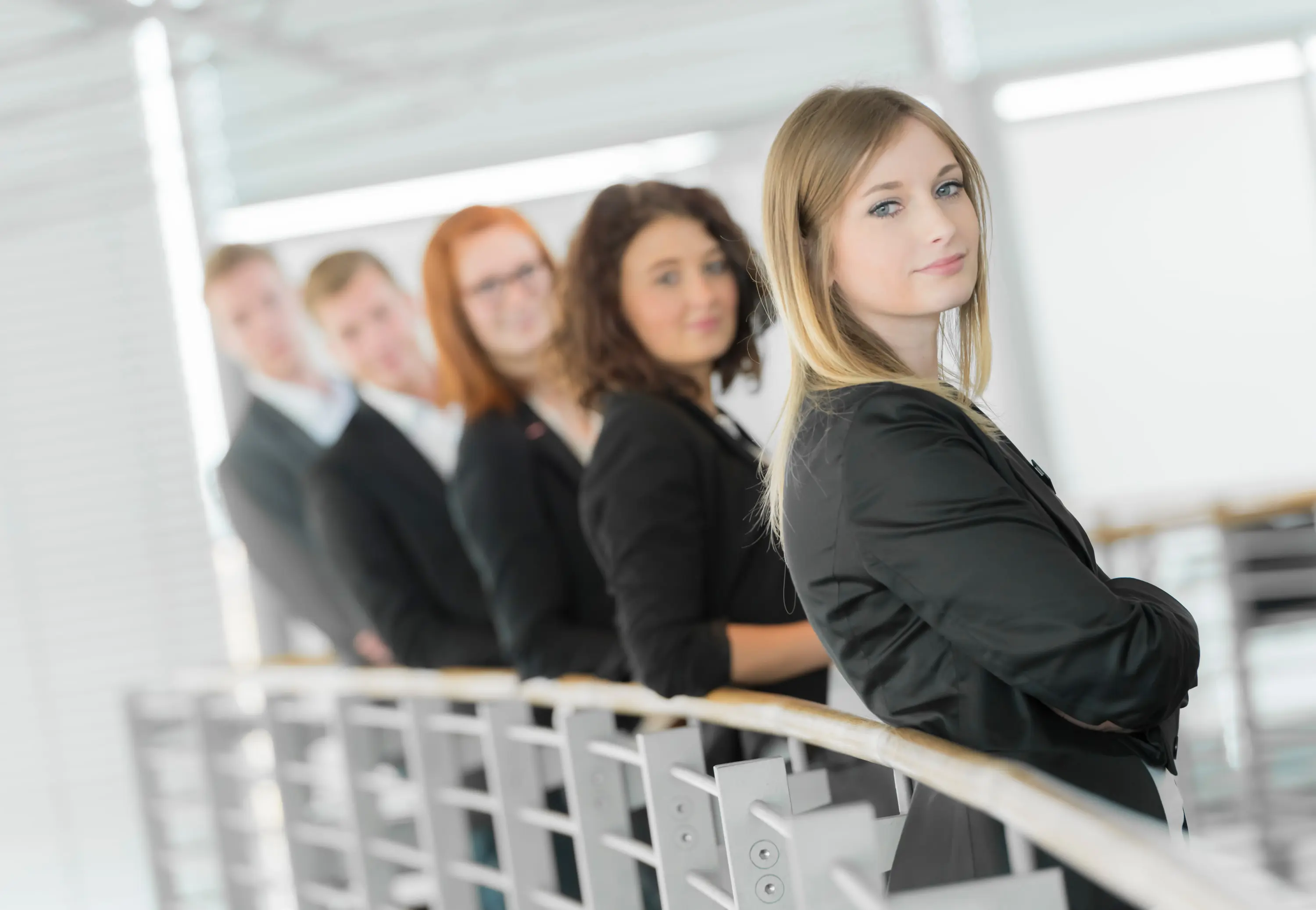 Team in Business-Kleidung lehnt am Geländer in einem Autohaus