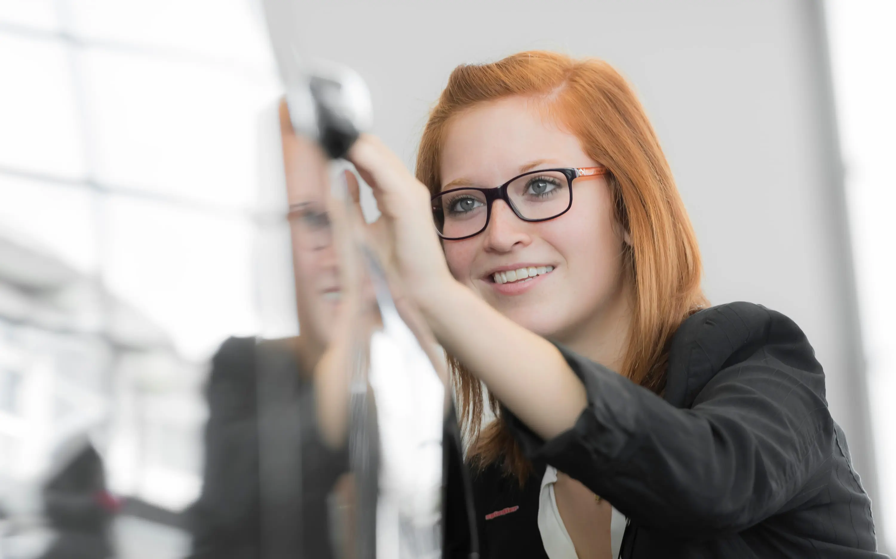Mitarbeiterin mit Brille schreibt an eine Glaswand in einem Autohaus