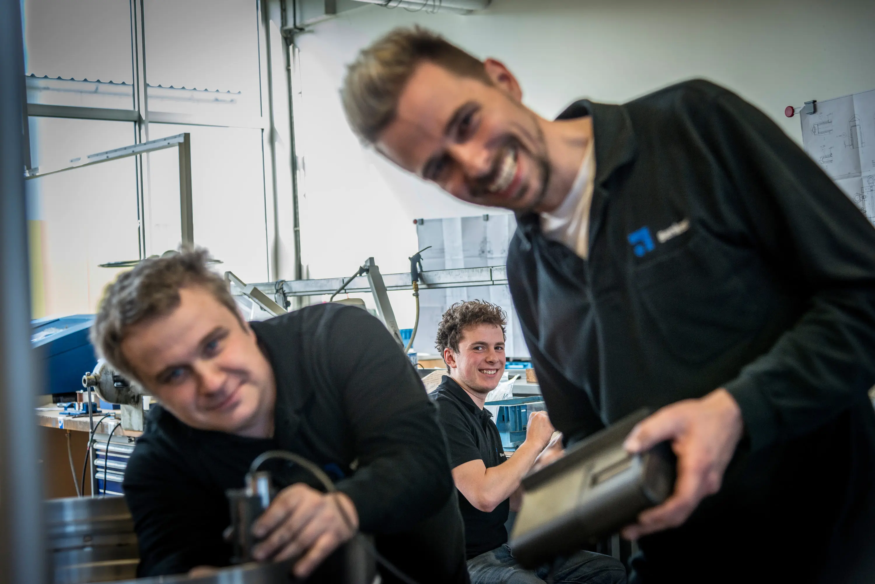 Zwei Mitarbeiter lachen bei der Arbeit in der Werkstatt eines Maschinenbauers