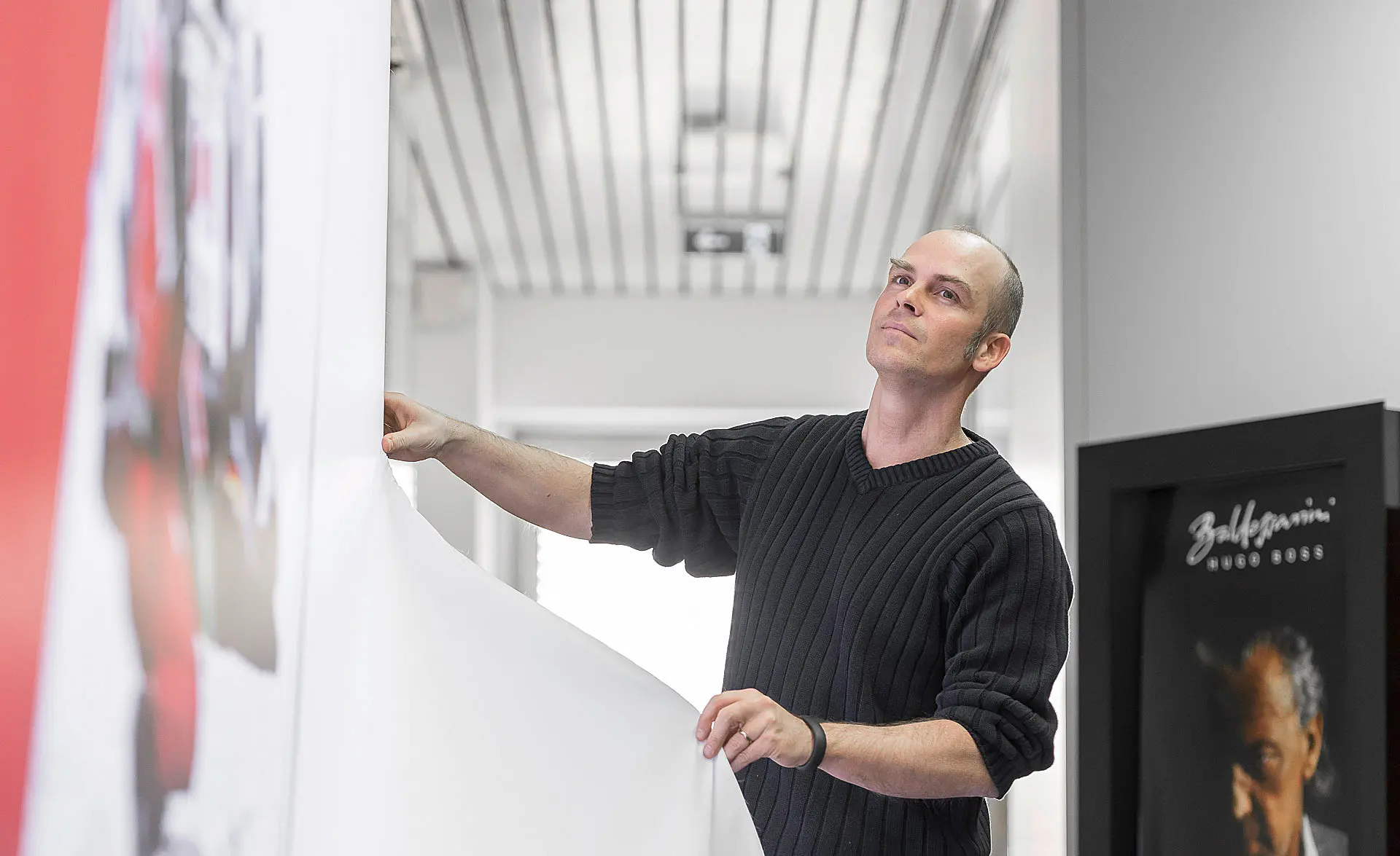 Mitarbeiter richtet ein großformatiges Plakat in einem Ausstellungsraum aus
