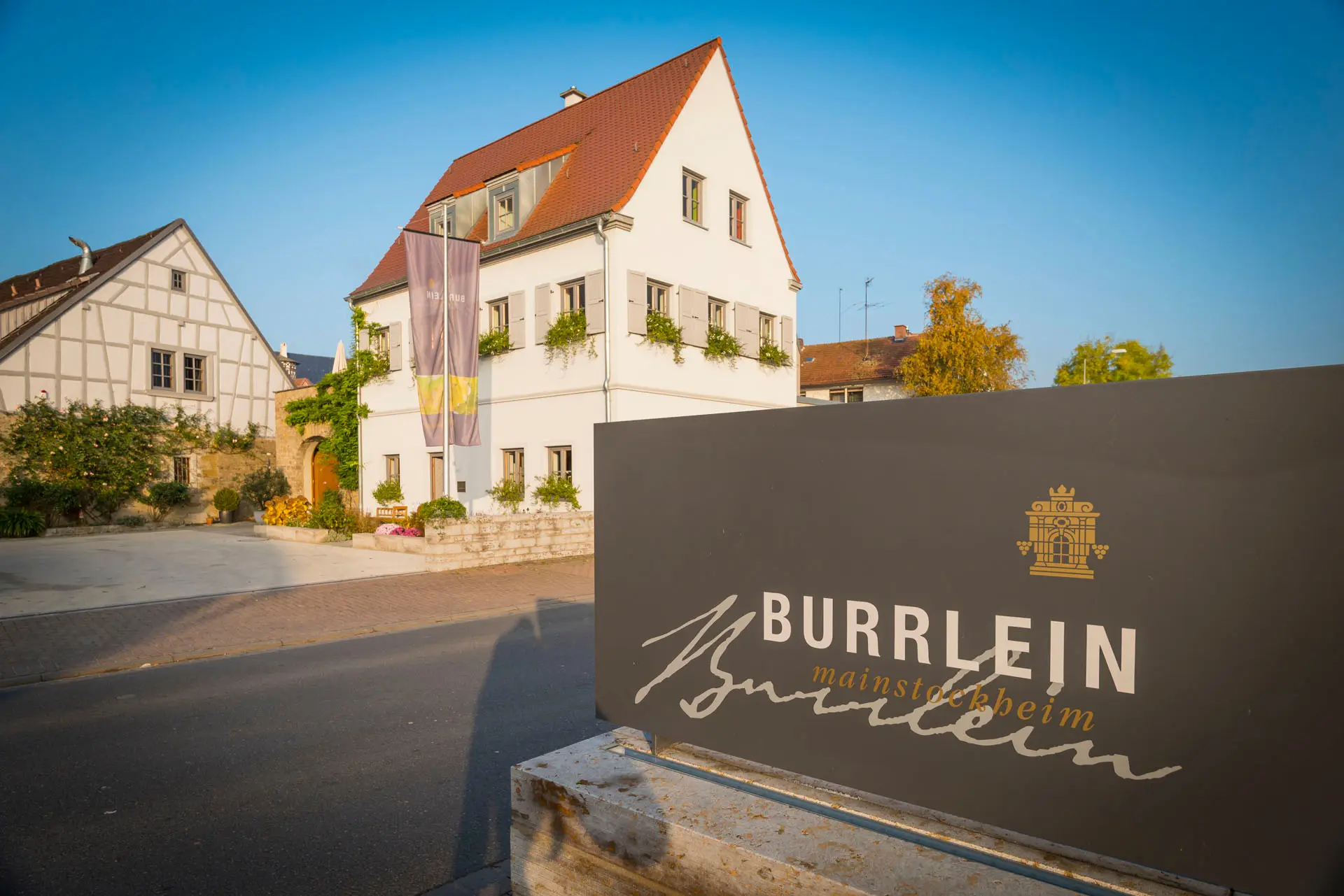 Hofeinfahrt des Weinguts Burrlein mit Schild und Fachwerkhaus