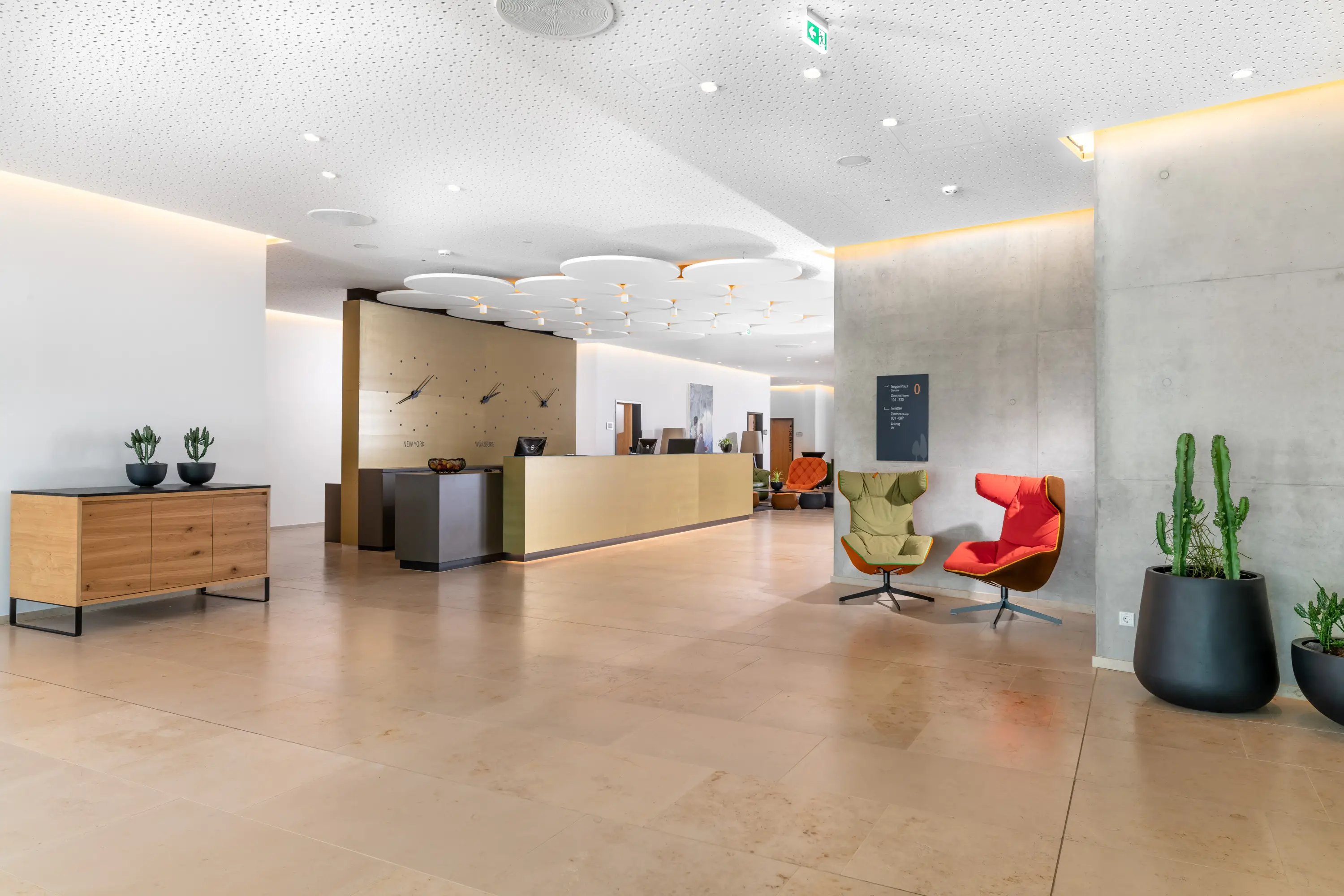 Lobby mit Rezeption und roten Sesseln, Hotel Melchiorpark Würzburg