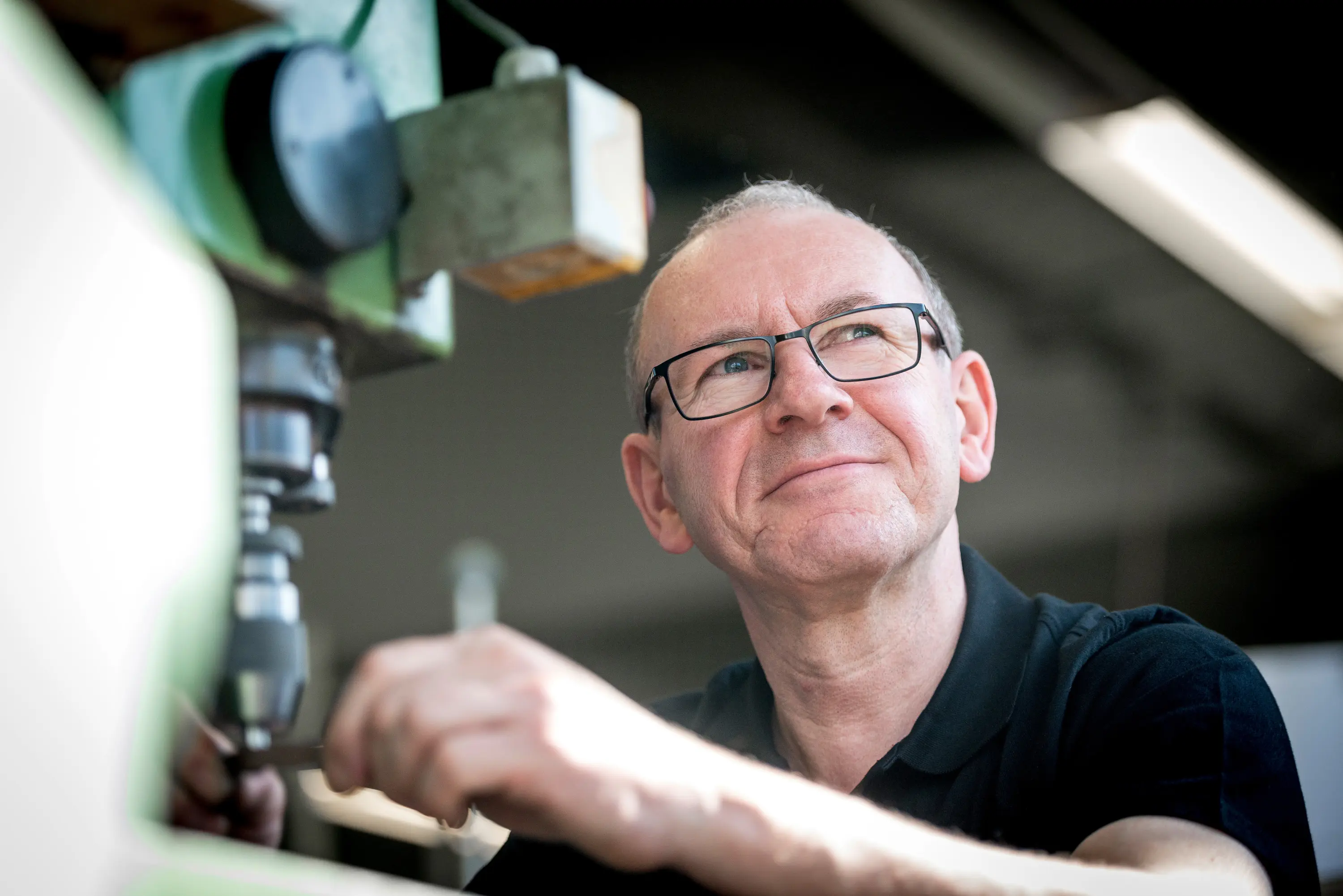 Mitarbeiter mit Brille arbeitet konzentriert an einer Maschine im Maschinenbau