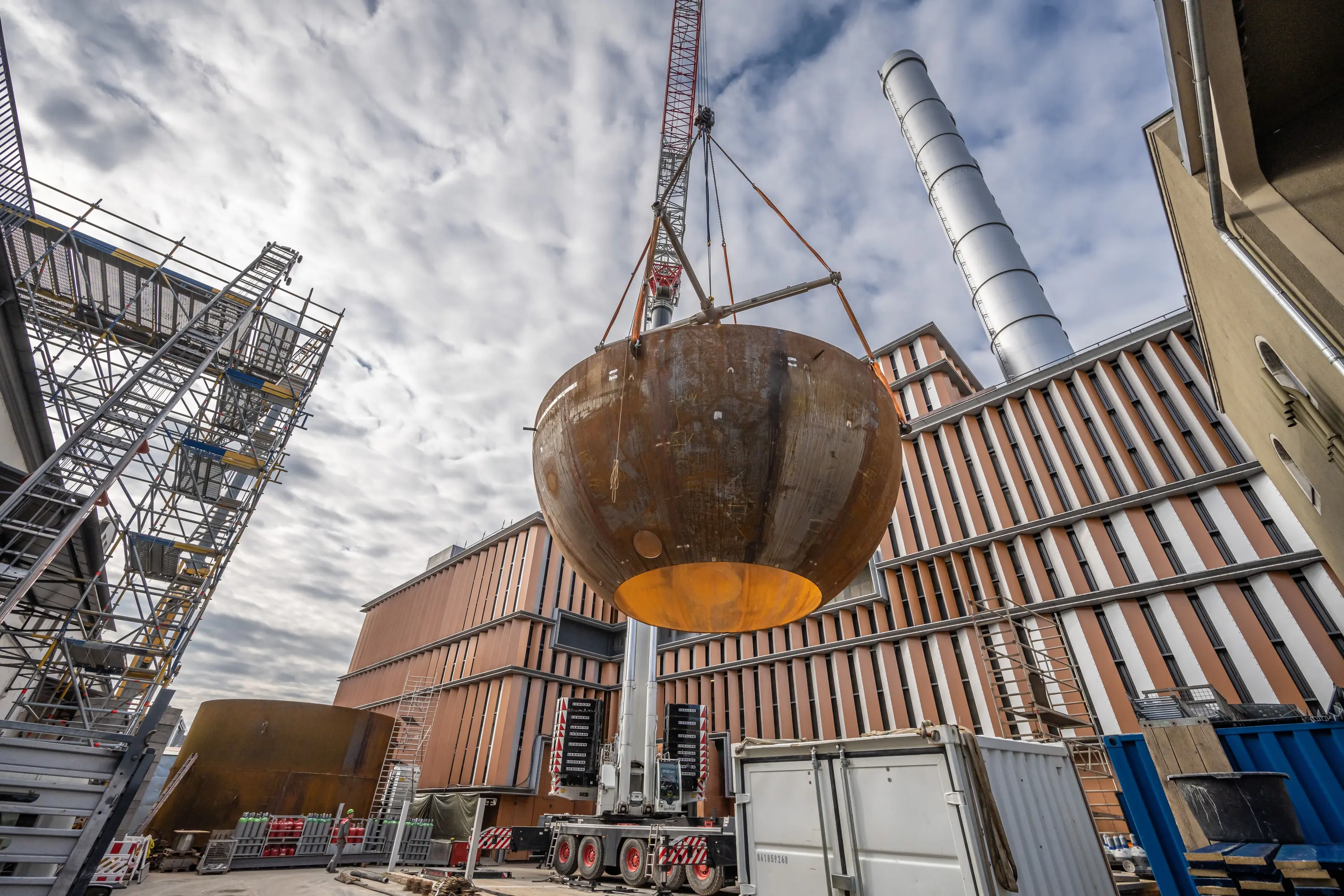 Kran hebt eine Stahlkuppel auf die Baustelle des Heizkraftwerks Würzburg