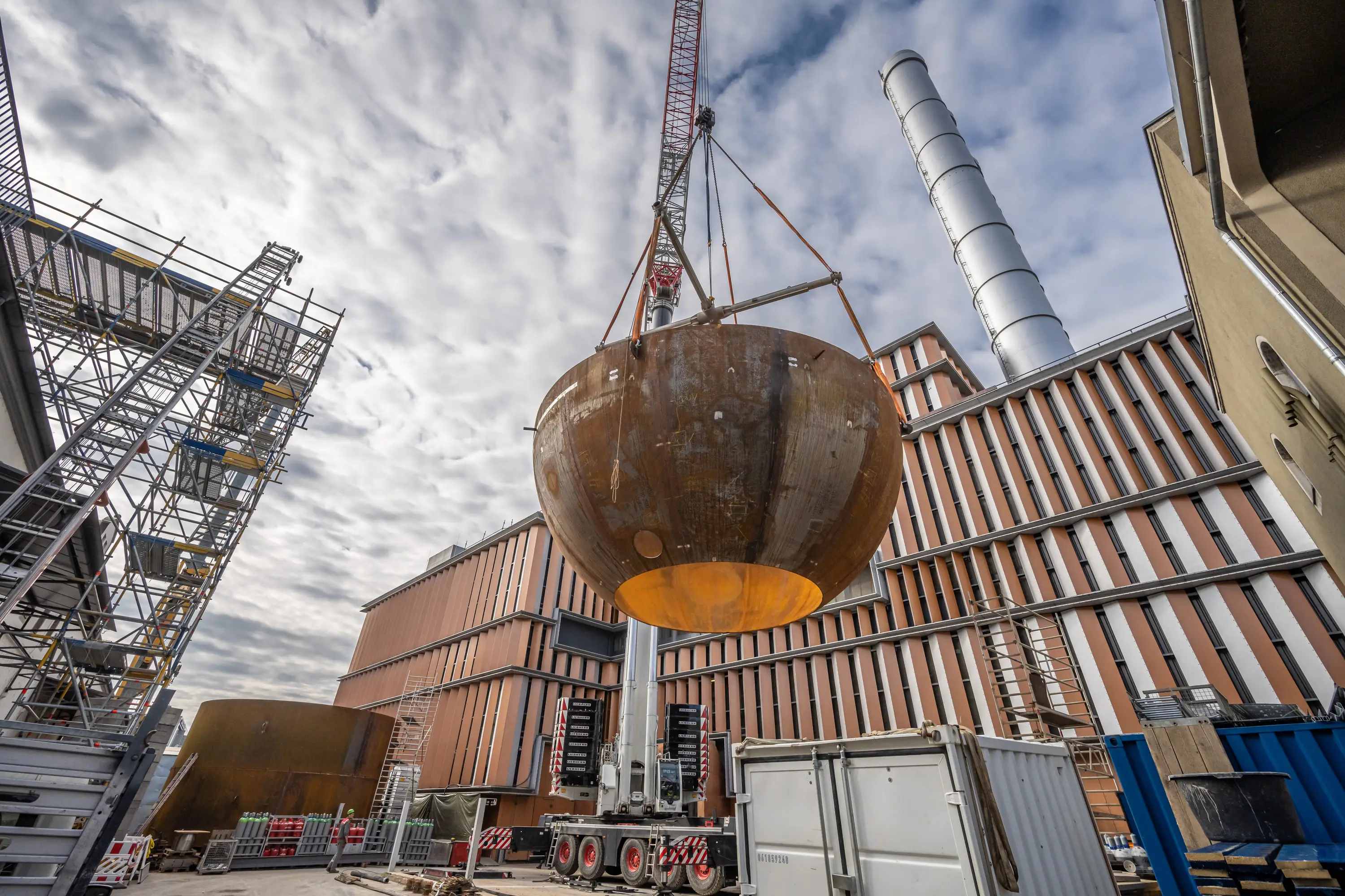 Kran hebt eine Stahlkuppel auf die Baustelle des Heizkraftwerks Würzburg