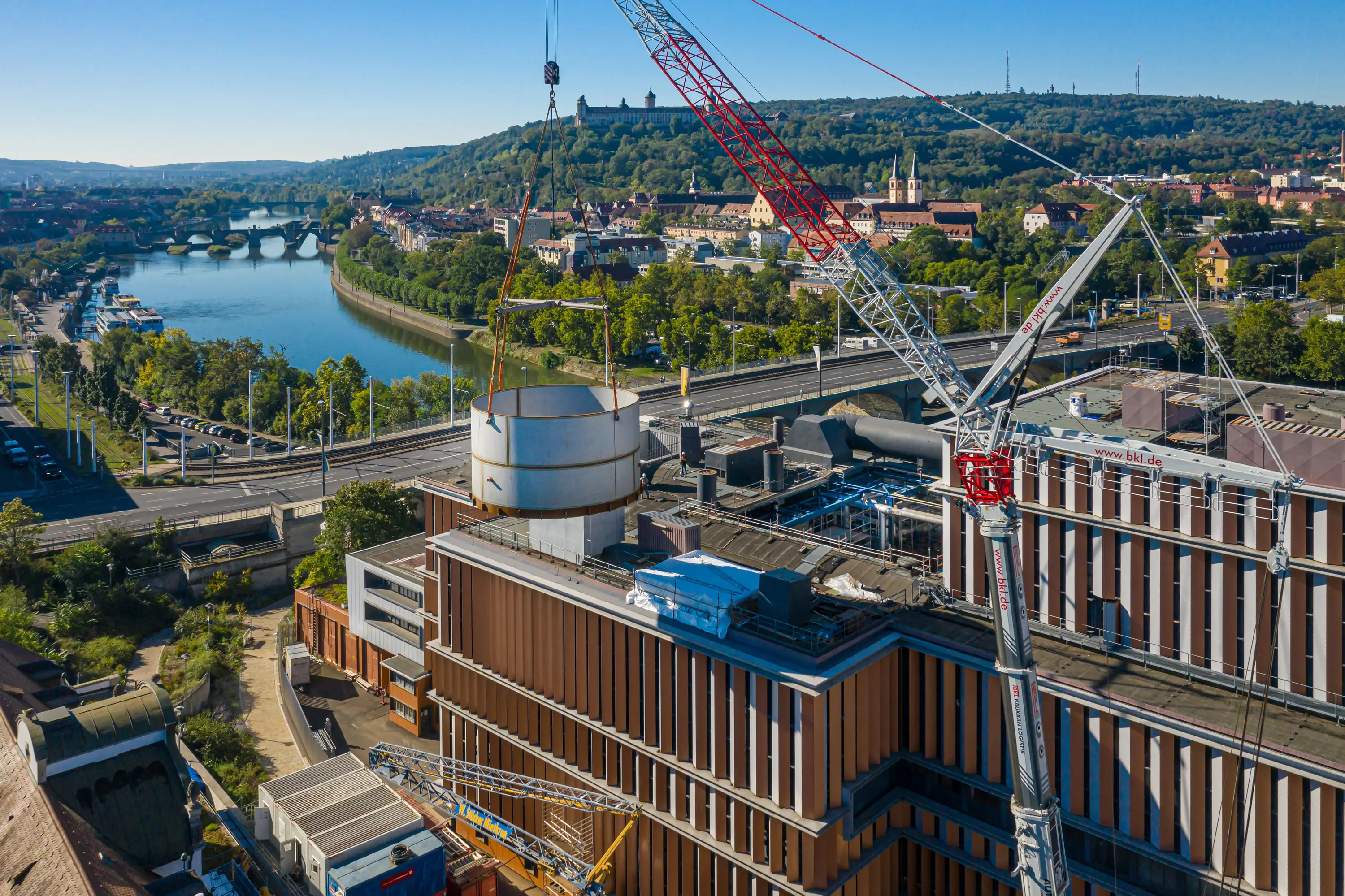 Baustelle des Heizkraftwerks mit Kran, dahinter Main und Würzburg